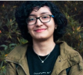 A woman with glasses and curly hair wearing a jacket.