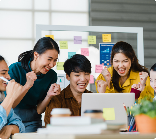 Three people are laughing and looking at a laptop.